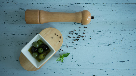 Olives, basil, pepper on blue timber background