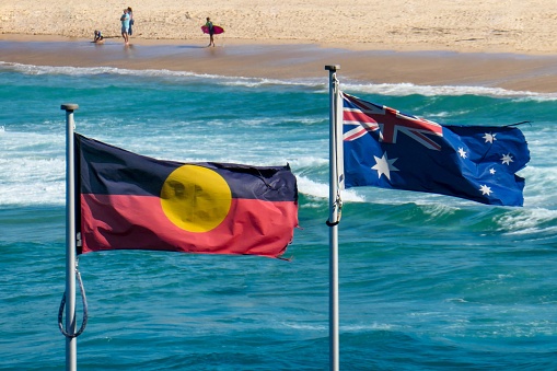 The Australian flag and Australian Aboriginal flag fly side-by-side at Bondi Beach, Sydney in early summer.  This image was taken on a windy day in the late afternoon.