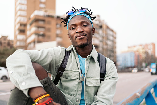 Young and confident african man sitting in the street and looking at camera.