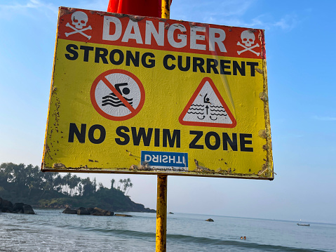 Despite the warning sign erected on the southern end of Bondi Beach, swimmers take to the water.   Uneven and inconsistent wave patterns and waves churning up sand are two indicators of dangerous currents, both visible in this image.  This area is under constant patrol by lifesavers and lifeguards.  This image was taken on an afternoon in summer.