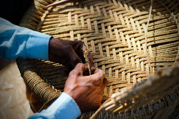 Skilled craftsman working manually a detailed bamboo wood armchair with his fingers and tools Skilled craftsman working manually a detailed bamboo wood armchair with his fingers and tools basket weaving stock pictures, royalty-free photos & images