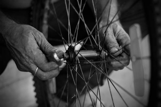 the old man working on motorcycle tire with tools close view in a service shop using finger in hands - bicycle chain bicycle tire black and white imagens e fotografias de stock
