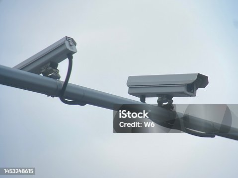 istock Surveillance cameras in front of blue sky 1453248615