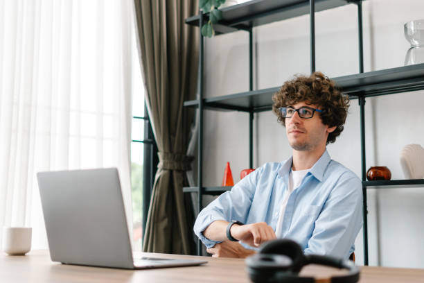 istock Young man sitting at desk, planning work with computer laptop in modern office 1453250434