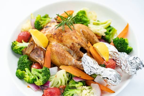 Closeup shot of a roasted chicken with vegetables on the white plate
