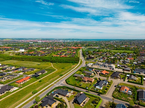An aerial drone shot of the beautiful town and the green vast fields under the blue clear sky