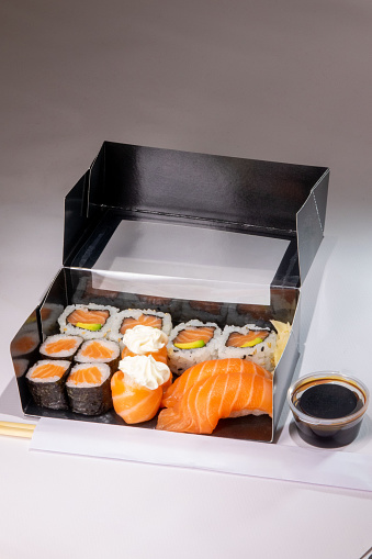 Sushi box with soy sauce and chopsticks on a white background