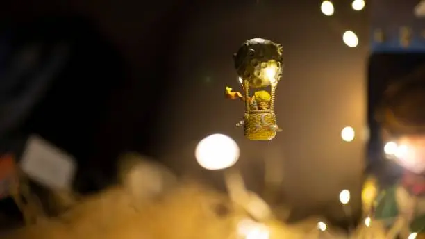 Photo of Small statuette of a little prince in a balloon in the shape of a moon floating in the air