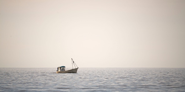 A lonely boat in the calm sea in the background of the endless horizon.