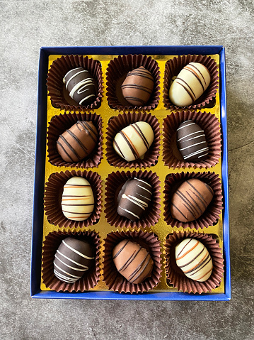 Stock photo showing a chocolate box display of individual, dates coated in dark, milk and white chocolate. Dates are a popular treat around the Christmas season.