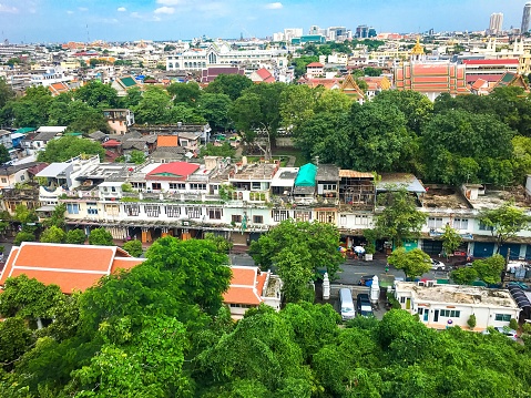 An aerial view of houses, street, and lush green trees in a town in Thailand