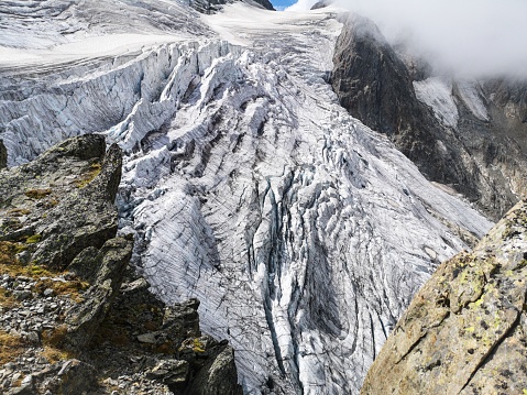 The mesmerizing view of The Stone Glacier in the Swiss Alps, its crevasses with snowy slopes, and fog in the background