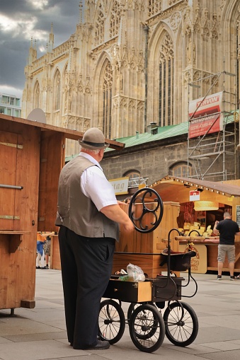 Vienna, Austria – May 26, 2022: Musician playing his organ grinder regardless of the upcoming thunderstorm in the historic Centre of Vienna facing St. Stephans Cathedral