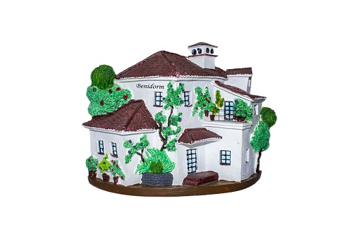 A decorative house shaped souvenir isolated on a white background with green trees
