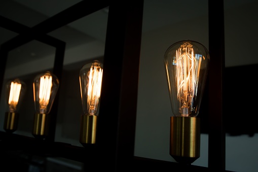 A closeup of modern lightbulbs on a contemporary chandelier with a dark blurry background