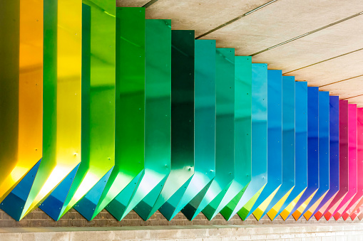 Happy 3D art, with colours ordered in a rainbow sequence and made of aluminium and concrete in a diagonal view, Paddington, London. High quality photo