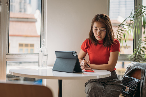 Portrait of beautiful Asian female office worker planning her schedule on smartphone