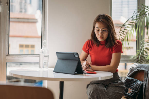 kobieta pracująca na tablecie cyfrowym w co working space . bizneswoman korzystająca z tabletu i smartfona. - czerwień zdjęcia i obrazy z banku zdjęć