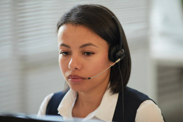 istock Woman wearing headset and looking at computer screen 1453276485