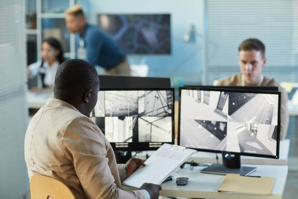istock Man looking at surveillance camera feeds at screen 1453276491
