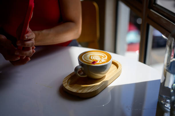 cup of hot latte coffee with latte art on table near window