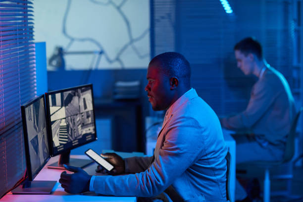 istock Black man looking at surveillance camera footage in security center office 1453276515