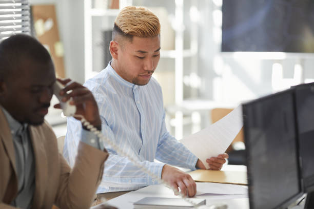 istock Young Asian man working with documents in surveillance center 1453276530