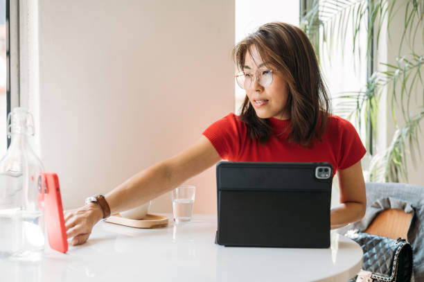 istock An Asian Woman sitting at Co Working Space working on smartphone and digital table 1453276543