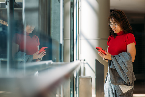 Shot of Asian businesswoman using a smartphone in a modern office.