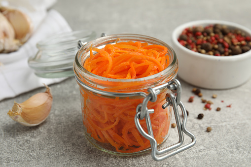 Delicious Korean carrot salad in glass jar on grey table