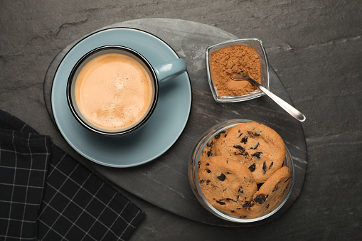 Chocolate chip cookies served with coffee on black table