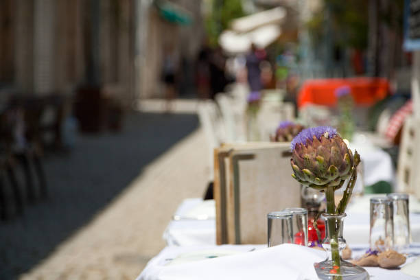 istock Glass vase with artichokes on table in open air restaurant 1453278738