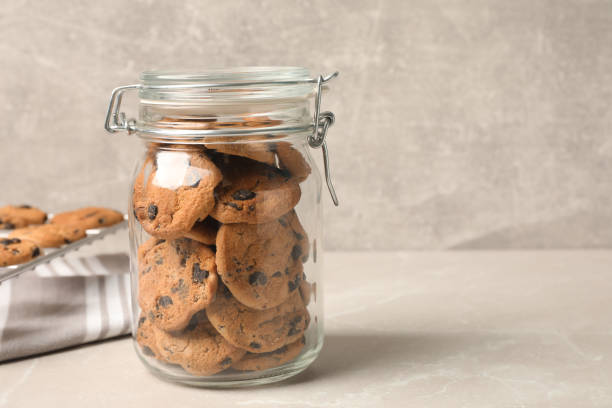 istock Jar of chocolate chip cookies on light grey table. Space for text 1453278922