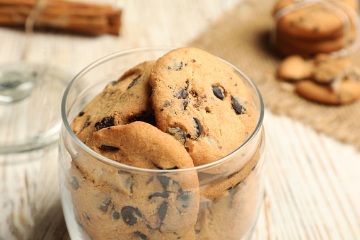 Jar of chocolate chip cookies on white wooden table, closeup
