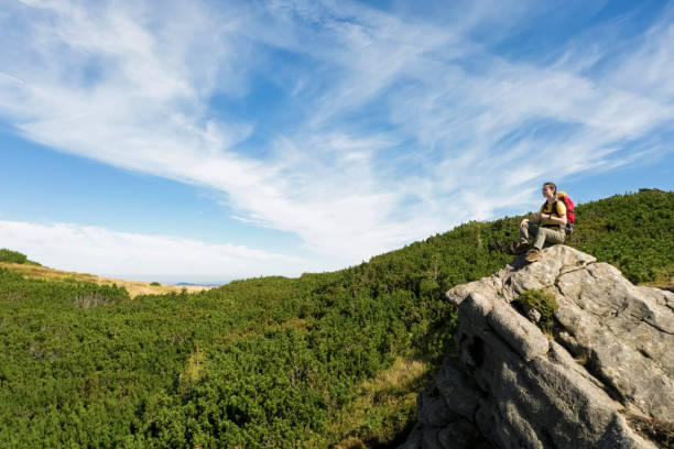 istock Young woman with backpack on rocky cliff in mountains 1453279083