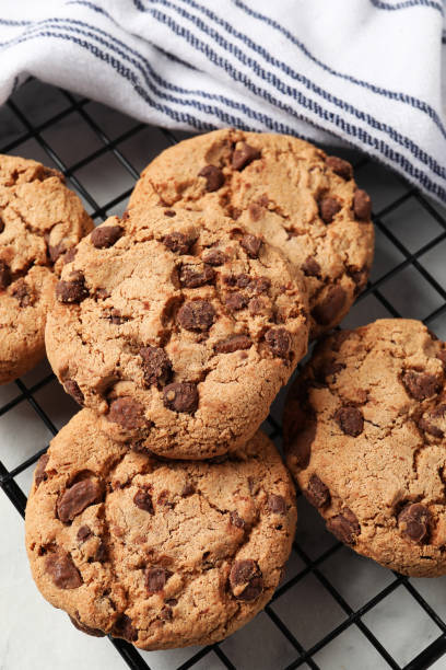 istock Cooling rack with delicious chocolate chip cookies on white table, closeup 1453279139