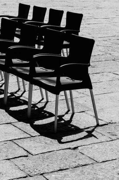 istock Vertical shot of many black empty chairs on a cobblestone 1453280386