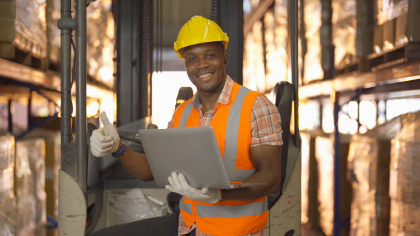 Portrait of black man worker working in large warehouse retail store industry factory. Rack of stock storage. Cargo in ecommerce and logistic concept. Depot. People lifestyle. Shipment service. retrato de un trabajador negro que trabaja en una gran fábrica de almacenes de la industria de tiendas minoristas. rack de almacenamiento en stock. carga en concepto de ecommerce y logística. depósito. estilo de vida de las personas. servicio de envío.