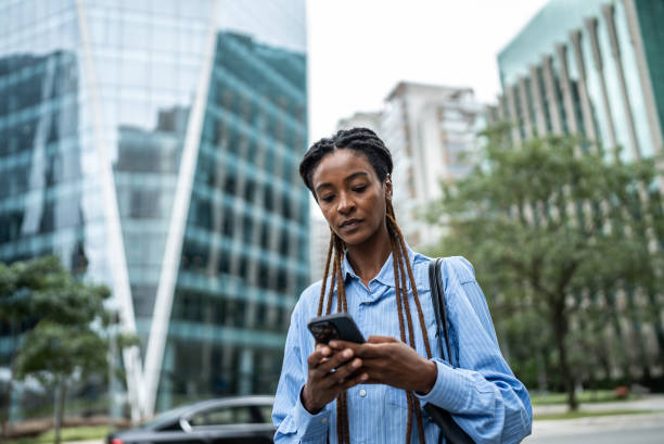 Young businesswoman walking in a financial district while using mobile