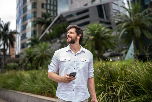 Businessman walking  in a financial district while using mobile phone