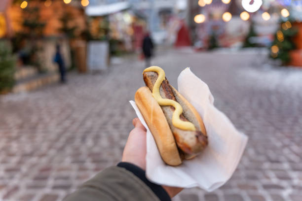 Unrecognizable man holding bun with sausage, at the Christmas market stock photo
