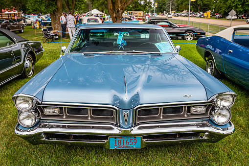 Iola, WI - July 07, 2022: High perspective front view of a 1965 Pontiac Grand Prix Hardtop Coupe at a local car show.