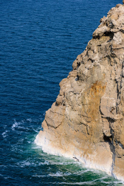 Dead Sea Water and Rock Cliff  with Salt Crystals showing Evaporation and Falling Sea Level