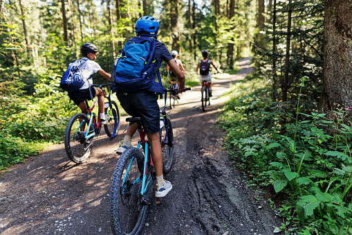 Mother and three teenage kids are enjoying a bike trip together in a forest\nCanon R5