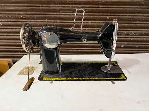 Stock photo showing close-up view of an old fashioned sewing machine on a table used as part of outdoor, roadside sewing business