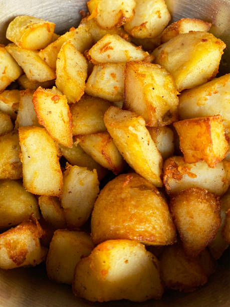 Full frame image of golden, fresh crunchy roast potatoes in metal bowl, bite size fried potato elevated view Stock photo showing an elevated view of the inside of a metal bowl with a pile of golden, freshly cooked roast potatoes. gold potato stock pictures, royalty-free photos & images