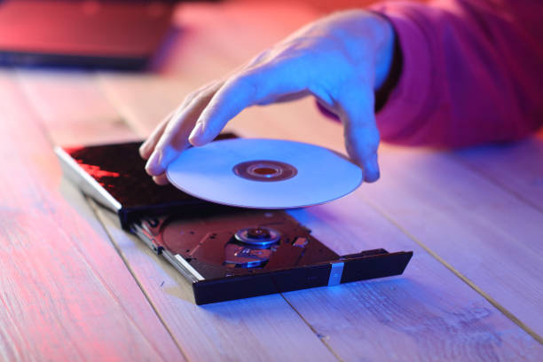 istock person inserting a compact disc into an optical drive into a laptop by a person 1453308052