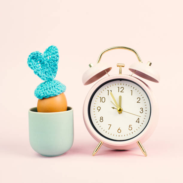 Cute easter bunny or rabbit in a cup with an alarm clock, spring holiday, greeting card