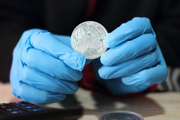 istock silver australian coin in hands with gloves over the table 1453308361