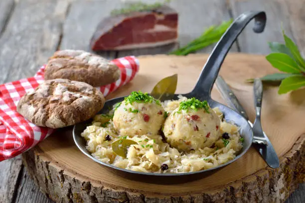 Delicious South Tyrolean bacon dumplings served on sauerkraut in an iron frying pan